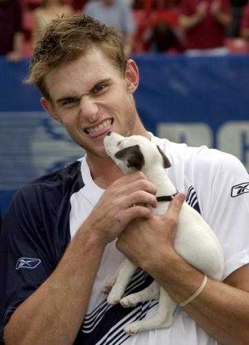 ANDY RODDICK  MAKES A FUNNY FACE DURING TROPHY PRESENTATION WITH RCA DOG